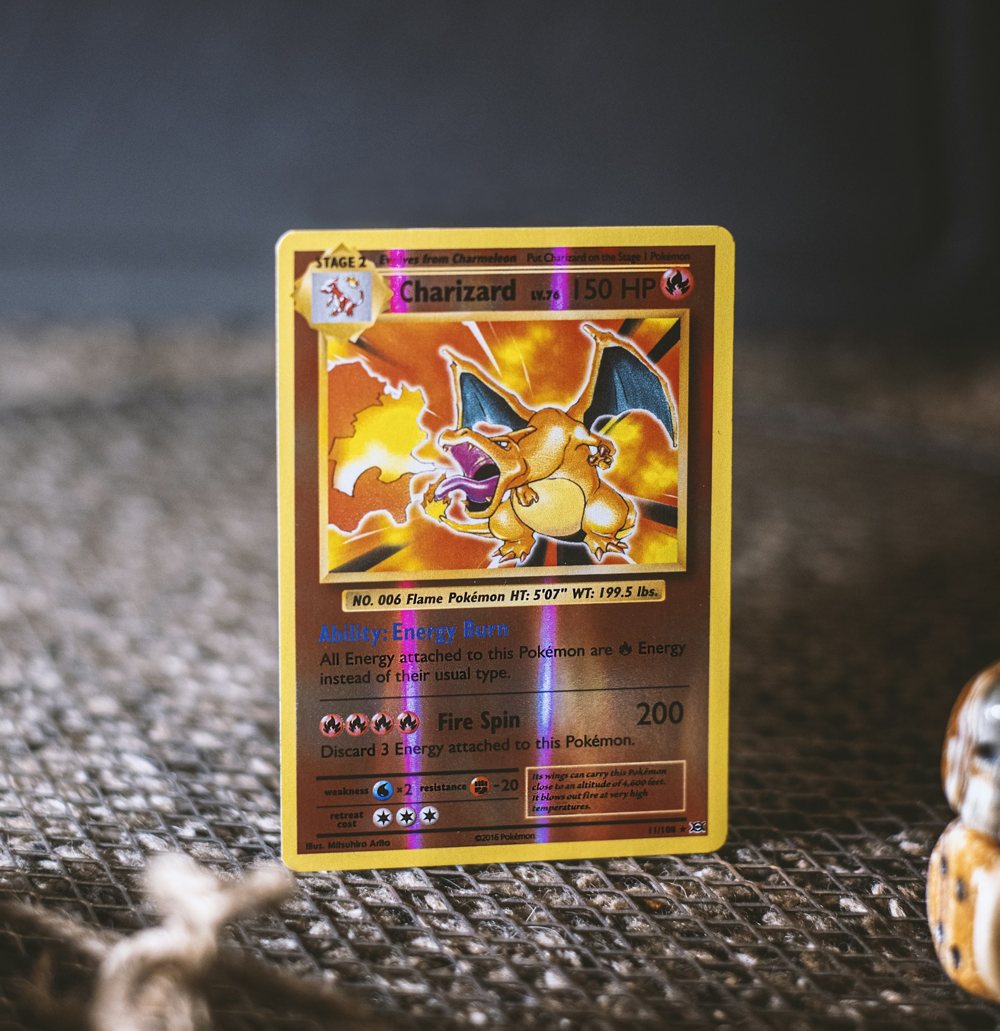 A holographic Charizard card standing on a gray cloth