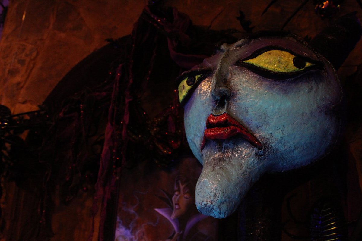 A large handmade witch mask with a pale blue face, yellow eyes and red lips, part of a home haunted-house display